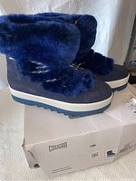 Side view of indigo blue Cougar boots with faux fur, sitting on original box showing brand and style.
