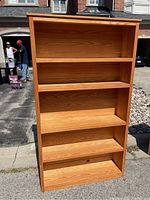 Front view of large solid pine bookcase showing five shelves and natural wood grain finish.