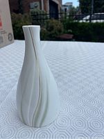 Front view of the white porcelain Royal Doulton Willow Wisp vase with curved vertical lines in green and gold.