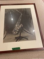 Framed black-and-white photo showing a tenor saxophone on a stand with visible signature and edition markings.