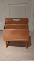 Front view of the vintage wooden magazine rack showing two deep magazine compartments and flat rectangular base with angled legs.