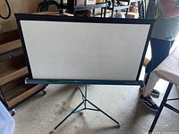 Full image of the blue collapsible movie screen pulled down on tripod stand