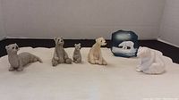 Six small bear figurines lined up including polar bears and brown bears on a beige cloth background.