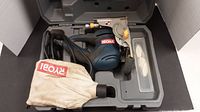 Ryobi biscuit joiner in grey molded plastic carrying case with dust collection bag and biscuit plates.