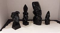 All four black obsidian sculptures grouped together on cloth backdrop