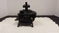 Black cast iron doll stove facing forward showing front details and text 'IRON IS VITAMIN'