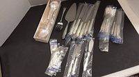 Assorted flatware pieces on black background, including forks, spoons, knives and serving utensils.