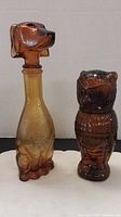 Front view of two amber glass animal bottles, dog on left and owl on right