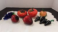 Top view of all 8 glass fruit figurines displayed on white cloth
