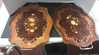 Top view of two inlaid wood trays showing scalloped edges, floral inlay, and brass trim.