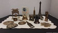 Wide view of all miniature brass landmark figurines and decorative pieces on a white cloth