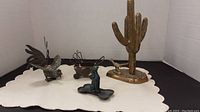 Full view of all five metal decorative items including brass cactus, bird, road runner, baby carriage, dog figurine