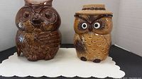Two ceramic owl cookie jars displayed side by side on a white surface.
