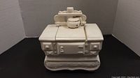 White ceramic cookie jar shaped like a vintage stove with detachable lid showing top burners and miniature kettle on stove surface.