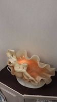 Front-left perspective of lamp showing glass shell interior glow and marble figure