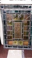 Close-up view of the unframed stained lead glass window showing amber textured glass blocks and blue decorative corners