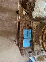Photo showing large rectangular and square wicker baskets stacked on each other on carpeted floor.