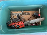 Craftsman chainsaw with accessories and tools inside green Sterilite storage bin