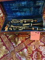 Top view of open case showing disassembled clarinet pieces inside, placed on a decorative patterned fabric.