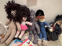 Five crocheted dolls including Cowardly Lion, Dorothy, Tin Man, Scarecrow, and a witch figure arranged in a line.
