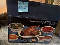 Original outer box showing Corningware Hostess Set branding with image of the set filled with food.
