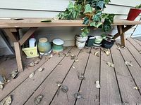 Photo showing various outdoor pots placed on a deck against siding wall