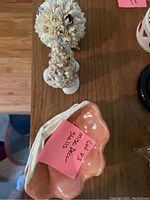Photo showing two shell cluster decor pieces and four stacked ceramic shell-shaped bowls with a peach interior and white exterior.