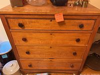 Front view of the antique dresser showing four drawers with wooden knobs and a wood finish.
