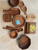 Wooden teakwood dishes, bowls, serving utensils and tray arranged on floor.
