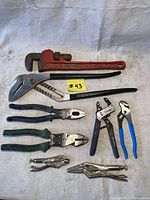All eight tools laid out on white cloth, showing the variety of wrenches and pliers in the lot.