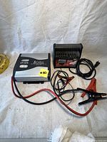 Photo showing both the NAPA battery charger and Cobra power inverter with associated cables and clamps on a white background.