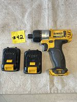 DeWalt 12V Max cordless screwdriver with 2 batteries, top-down view, showing tool, two batteries, and item number tag