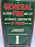 Front view of the green metal perpetual calendar with company branding and January month card held in a slot above a day card showing number 1.