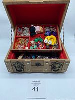 Wooden treasure chest box open showing mixed assorted costume jewellery inside top compartment and lower drawer, red fabric lined interior.