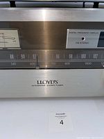 Close-up of Lloyd's stereo tuner silver face showing frequency scale and brand.