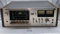 Front view of Sony cassette deck showing the cassette compartment, analog VU meters, control buttons, and volume knob