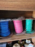 Three spools of colored insulated wire in blue, pink, and green.
