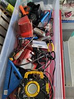 Top-down view of bin filled with assorted tools including a work light, drill, screwdrivers, pliers and accessories.