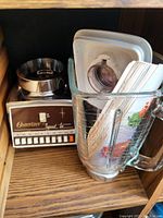 Photo of vintage Osterizer blender, glass jar with lid, and metal mixing bowl on wooden surface.