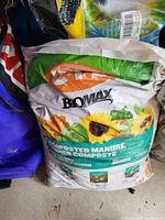 Image showing a sealed bag of BoMax Composted Manure soil amendment with branding and product info visible.