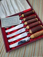 Set of six cutting utensils with German steel blades and bone handles inside a red textured leatherette box with white satin lining