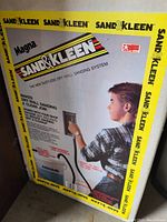 Photo of Sand & Kleen Magna drywall sanding system box showing branding and image of user operating the sander on a wall.