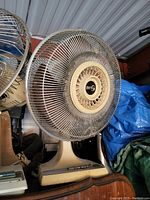 Full view of a vintage beige table fan with metal protective grill and plastic base with control buttons