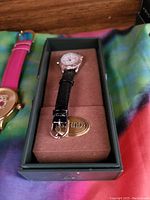 Guess men's wristwatch with round silver-tone case, white dial showing three subdials, black leather strap inside Guess branded cushion and case.