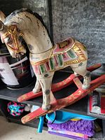 Wooden rocking horse on red curved base with multicolor paint details.