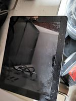 Front view of the iPad showing a cracked glass screen and reflections from surrounding area.
