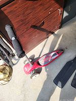 Red kids scooter with two wheels visible in front and one rear wheel, foam handle grips, and textured foot deck.