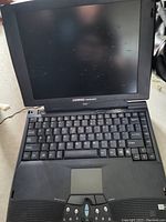 Front open view of Compaq Presario 1200 laptop showing keyboard, screen, and touchpad with some wear and dust.