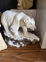 Photo of a white polar bear figurine standing on a textured base resembling rocks and snow.