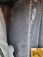 Photo of a black queen mattress showing side and surface quilted fabric with some reflections.